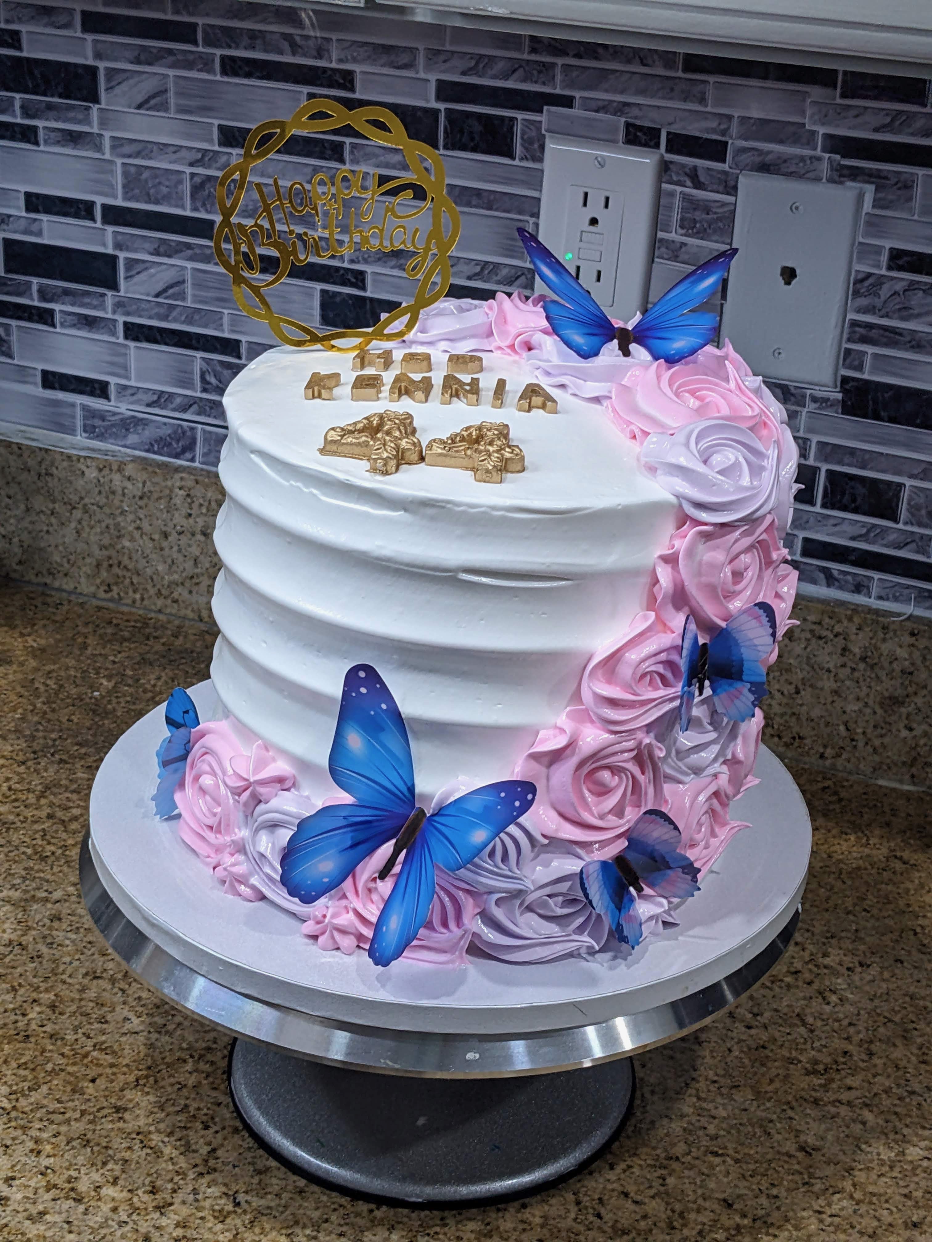 Pastel blanco con flores rosadas y mariposas azules